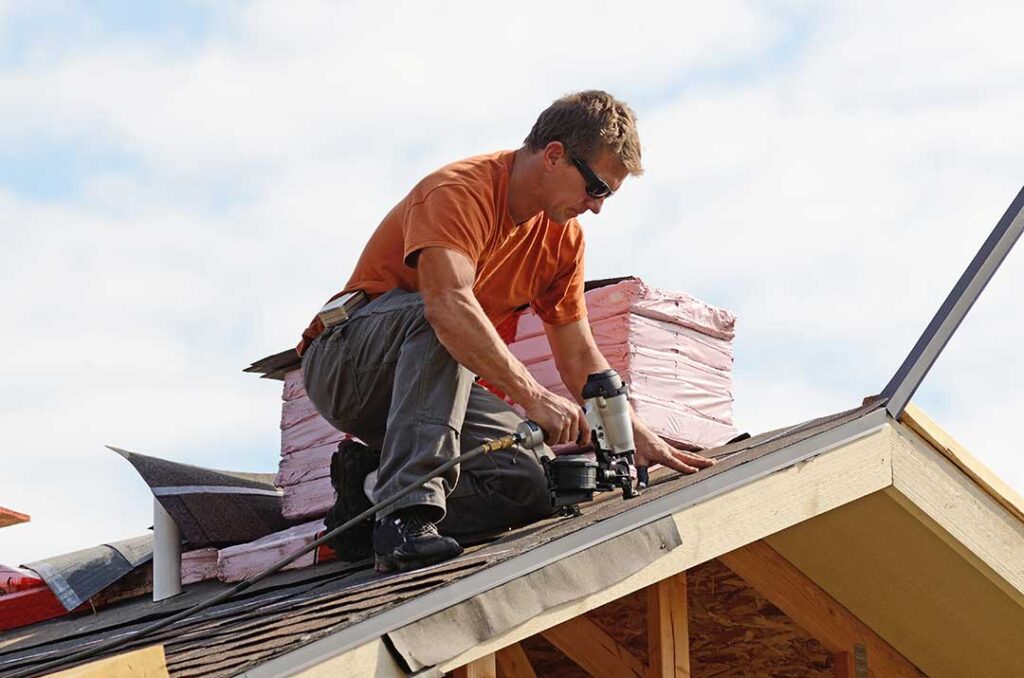 Homeowner examining shingles and flashing from the ground after winter weather.